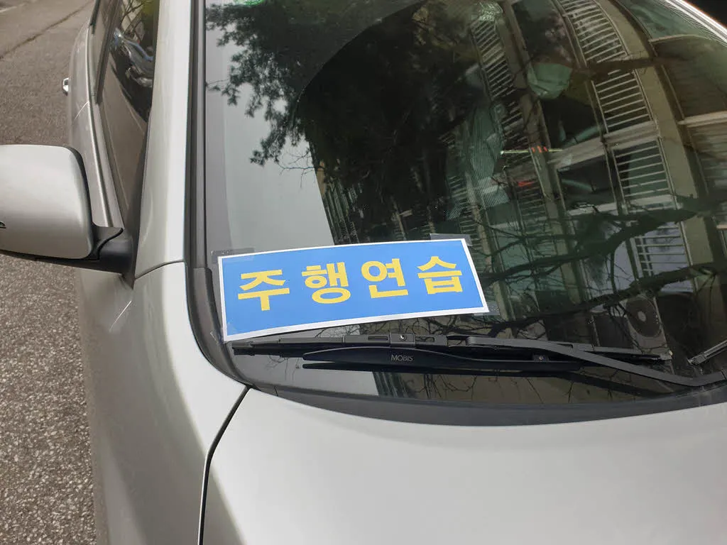 전면 유리 우측 하단에 붙인 도로 주행 연습 표지