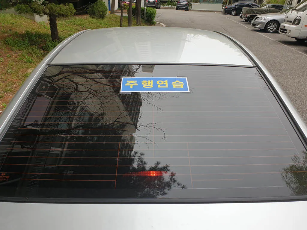 후면 유리 중앙 상단에 붙인 도로 주행 연습 표지