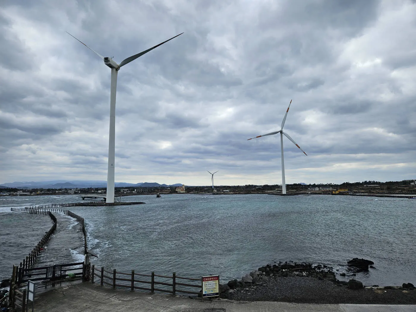 구름 낀 하늘과 풍력발전기 그리고 거친 바다.